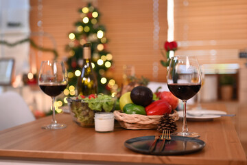 Glasses of red wine, roasted turkey and all sides dishes in decorated room with a Christmas tree. Thanksgiving table or Christmas dinner