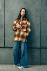 young woman leaning against the wall in autumn clothes