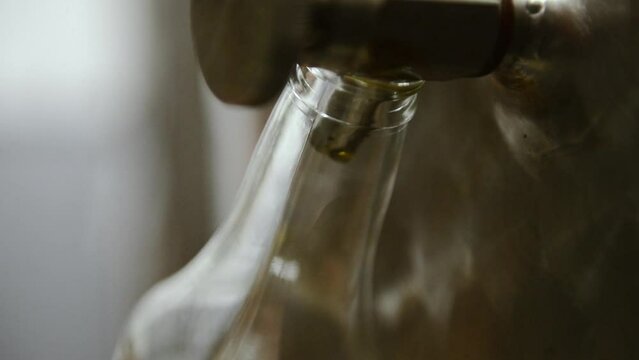 Huile d'olive transvas&eacute;e de la cuve vers la bouteille avec gouttes qui brillent &agrave; la lumi&egrave;re