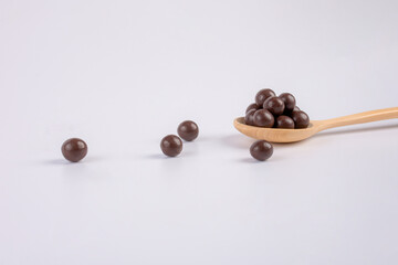 Chocolate balls on wooden spoon on a white background. 