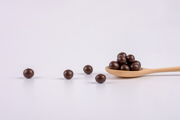 Chocolate balls on wooden spoon on a white background. 