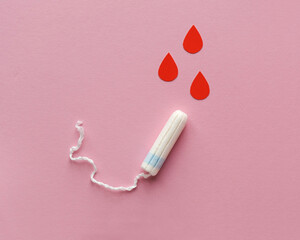 Feminine hygienic tampon and drops of blood on pink background. Menstrual cycle