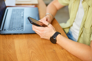 Fototapeta premium Businessman holding smartphone sitting in office, using cell phone mobile apps and laptop