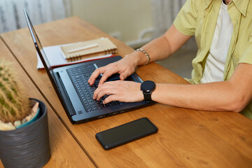 Man hands typing something on laptop, working on computer at home