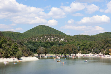 View of cypress lake in Sukko, Russia. Tourists on catamarans and boats.