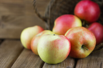 Close-up view of red apples spill out of the basket on wooden background