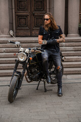 Fototapeta na wymiar Shot of trendy man looking like rocker and his old fashioned motorcycle.