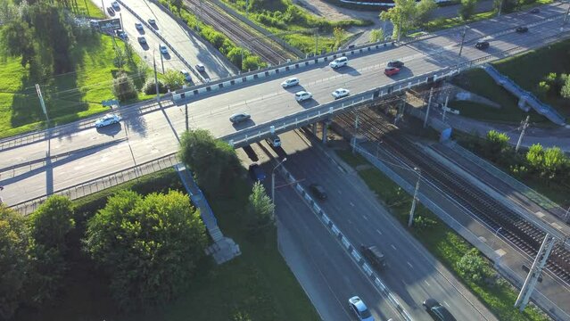 4k Top view of cars drive on intersecting roads in countryside irrl. Above pic of lot of transport driving on freeway surrounded by green trees on summer day. Beautiful picture from flying drone of