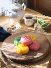 A variety fragrant colorful traditional Asian snow skin mooncake with a cup of tea and porcelain in background. Usually eat chilled and served to celebrate Mid-Autumn Festival