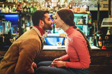 Foto op Plexiglas Couple of romantic young people rubbing noses sitting at pub's counter © Lomb