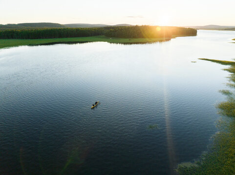Aerial view of a canoe sailing the Torne River at sunset in Overtornea, Norrbotten, Sweden.