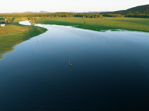 Aerial view of a canoe sailing the Torne River at sunset in Overtornea, Norrbotten, Sweden.