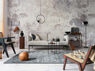 Loft style of modern apartment with grey design sofa, armchairs, ladder, black coffee table, black ladder, pedant lamp, carpet, decoration and elegant accessories . Concrete grunge wall. Template.	