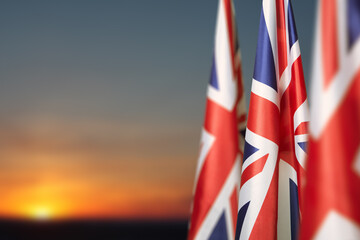 National flags of United Kingdom on a flagpole on sunset sky background. Lowered UK flags. Background with place for your text.
