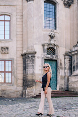 A young, slender blonde in beige pants and a black blouse walks the old streets of Lviv. Ukraine.