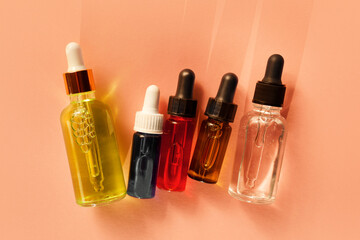 Five different glass dropper bottles with serum, oil, gel and beauty products on beige background. Pipette with fluid hyaluronic acid, retinol, vitamin c and a. Natural cosmetics, healthcare, bodycare