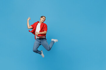 Fototapeta na wymiar Full body young man of African American ethnicity he wear red shirt jump high pretending playing guitar do hands gesture isolated on plain pastel light blue cyan background. People lifestyle concept.