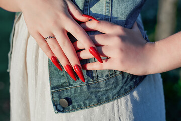 Female hands with red stiletto nail design. Glitter red nail polish manicure. Young female with...