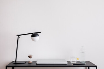 nterior design of simple and modern workspace with copy space, dark desk, table lamp, laptop,...