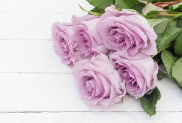 bouquet of five beautiful purple roses on a white wooden background