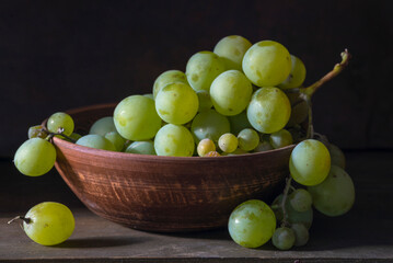 organic ripe seedless green grape clay ceramic dish bowl pot  wooden table Still life Close up rustic orange blue light.