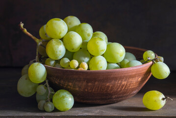 organic ripe seedless green grape clay ceramic dish bowl pot  wooden table Still life Close up rustic orange blue light.
