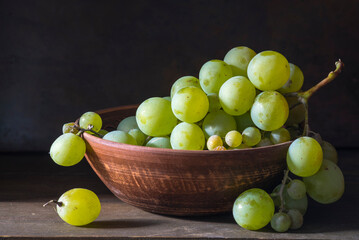 organic ripe seedless green grape clay ceramic dish bowl pot  wooden table Still life Close up rustic orange blue light.