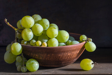 organic ripe seedless green grape clay ceramic dish bowl pot  wooden table Still life Close up rustic orange blue light.
