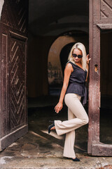 A young, slender blonde in beige pants and a black blouse walks the old streets of Lviv. Ukraine.