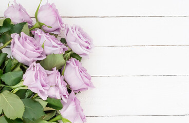 bouquet of beautiful purple roses on a white wooden background,with a copy of the space