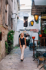 A young, slender blonde in beige pants and a black blouse walks the old streets of Lviv. Ukraine.