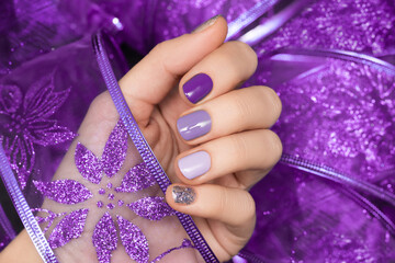 Female hand with magic nail design. Glitter purple nail polish manicure. Female hand hold purple...