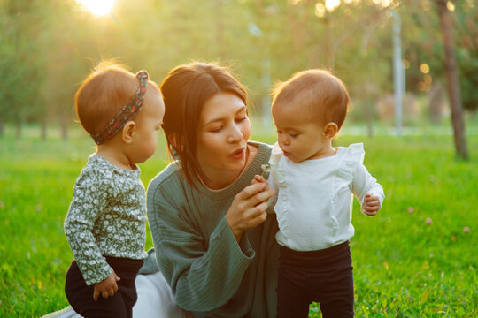 Mother with twin toddlers blowing dandelion