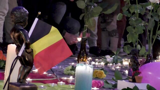 People paying tribute after Brussels terror attacks - Candles, flowers, Manneken Pis statue with Belgian flag - March 22 2016 - Brussels, Belgium