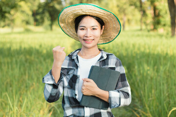 Asian farmer woman standing and thumb up at green rice farm