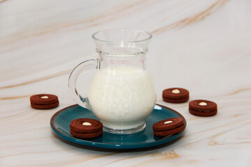 white fermented milk drink ayran in a transparent glass mug and chocolate cookies on a blue plate