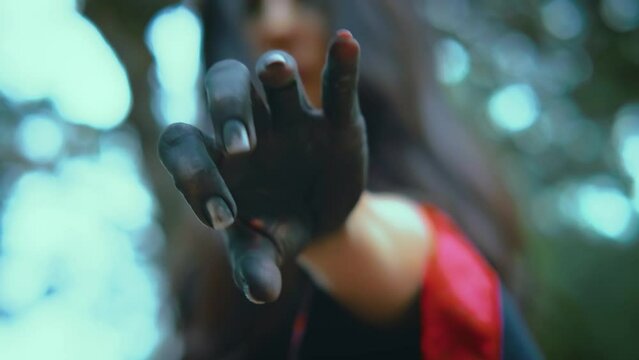 Fantasy woman witch waving hand looking at camera close-up beckons, calls gesture of invitation. Arm, fingers stained with black color paint ashen. Girl vampire glamour. Gothic Black dress. Body part