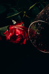 overturned glass of wine and red rose, low key, background