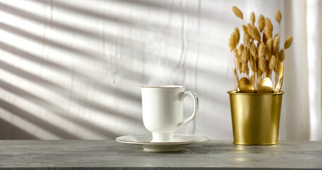 Coffee on the white kitchen table, sun shadows on the wall and empty space