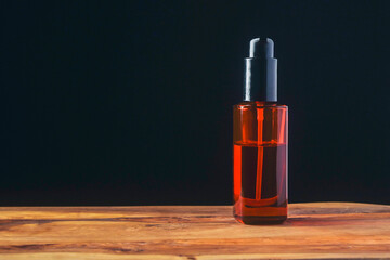 Naklejka premium Brown plastic oil spray bottle. Man grooming accessories on a wooden board, dark background. Hair and beard styling. Still life. Copy space.