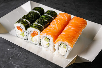 delicious sushi rolls in a delivery box on a black background