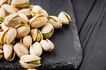 fresh salted pistachios on a black stone wooden rustic background