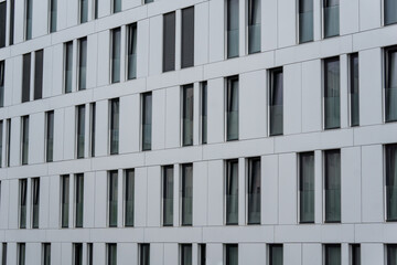 white facade of modern building with many black windows 
