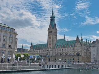 Fototapeta na wymiar The Hamburg City Hall with the river and flags in the foreground