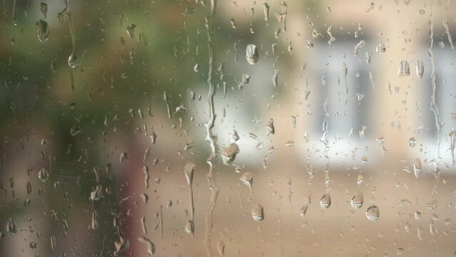 Raindrops run down the glass. Rain drops on the window closeup. View from window. Rainy day. Close up view of water drops falling on glass.