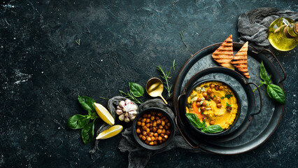 Hummus from chickpeas and carrots, with olive oil and spices. Top view. On a black background.