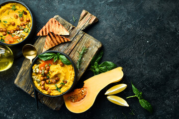 Hummus from chickpeas and pumpkin, with olive oil and spices. Healthy vegetarian food. On a black background.