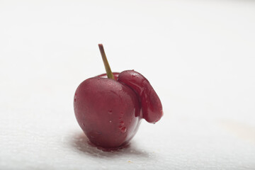 Red black cherry on white background with water drops. With appendix. Ugly crooked fruit.
