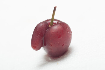 Red black cherry on white background with water drops. With appendix. Ugly crooked fruit.
