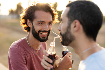 Gay couple embracing and showing their love. Young men drinking juice.